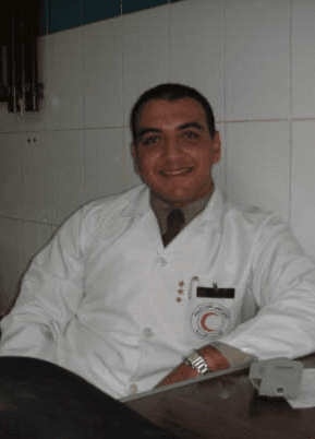 Mr Sherif Elshazly seated at a desk wearing a white clinical coat