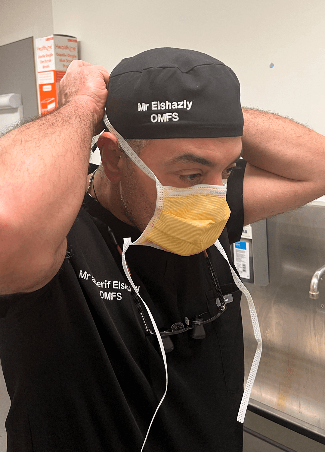 Mr Sherif Elshazly fastening a surgical mask in a hospital scrub room