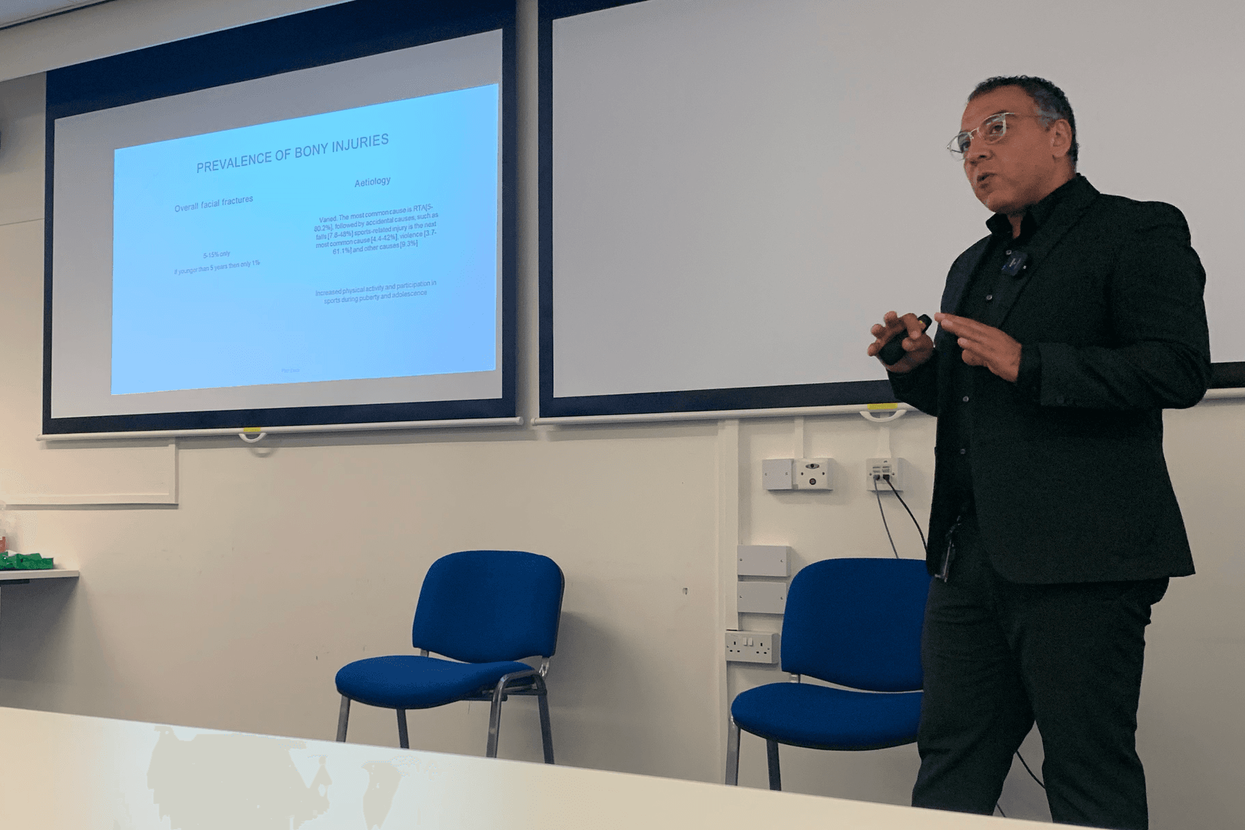 Mr Sherif Elshazly presenting a postgraduate teaching session beside a projected slide